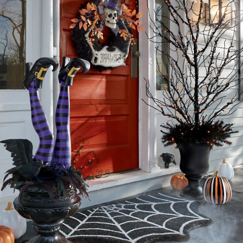 Two resin witch leg stakes with striped stockings and black boots in a garden bed