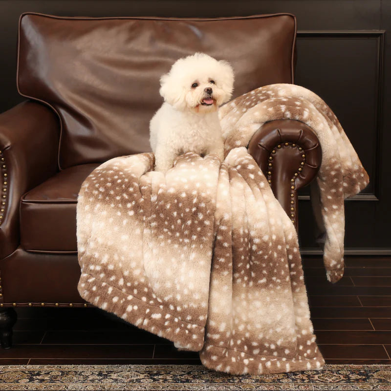 Beige faux fur blanket with deer pattern draped over a bed