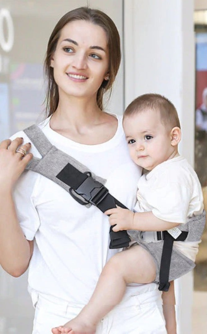 Woman wearing the gray hip seat baby carrier