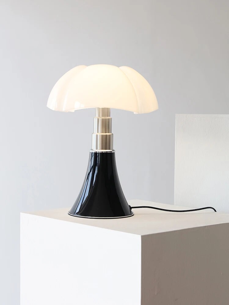 The dimmable flower desk lamp casting a warm glow on a bedside table next to a book.