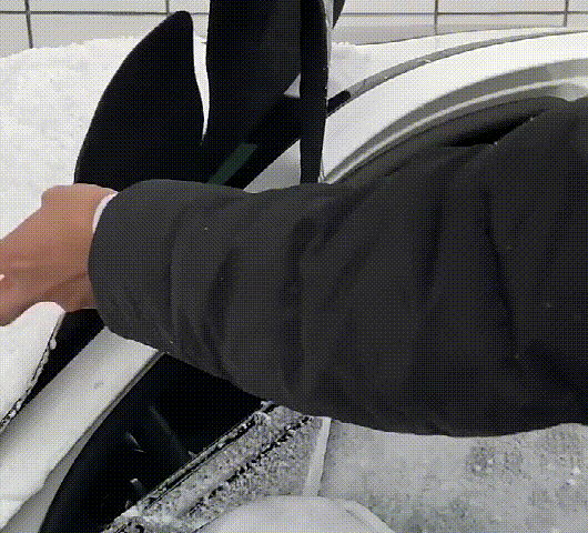 Windshield cover being pulled off a car on a winter morning