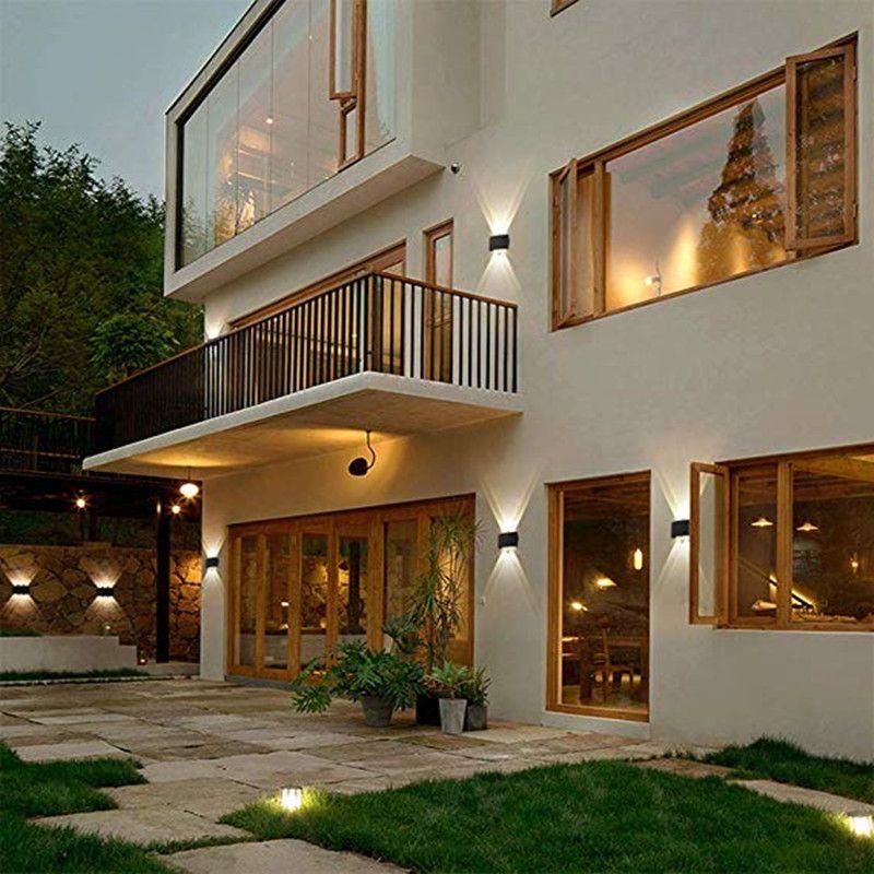 Black outdoor LED wall light glowing next to a front door at night