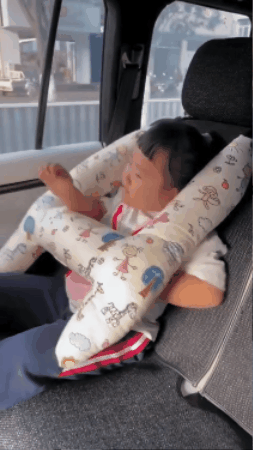 Child sleeping in a car seat with a soft animal neck pillow