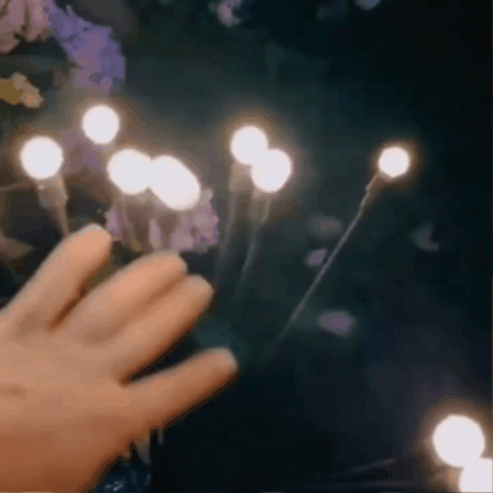 Solar firefly garden lights glowing between plants at night