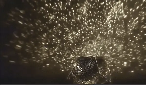 Star projector casting a starry sky onto a bedroom ceiling