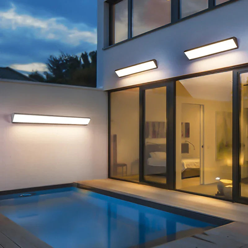 Black aluminum LED wall light mounted next to an entrance