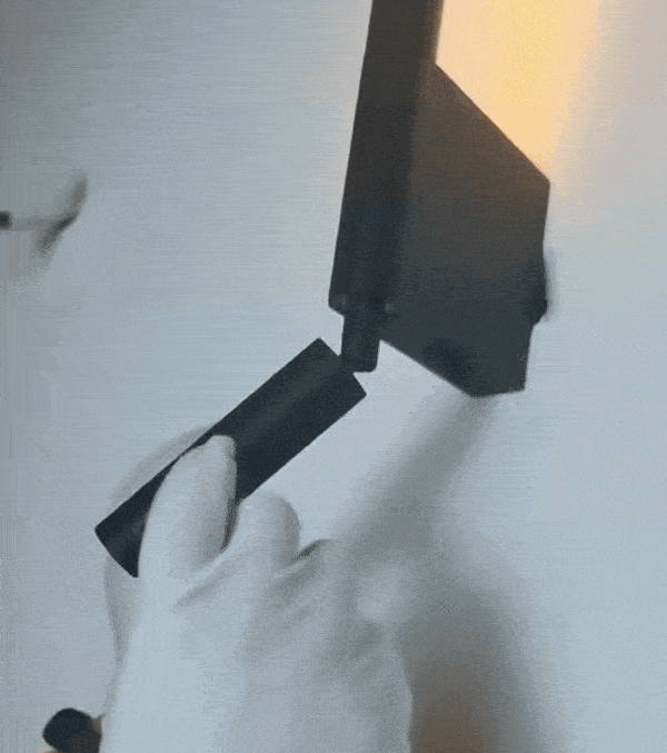 Slim black LED wall sconce lighting up a hallway wall