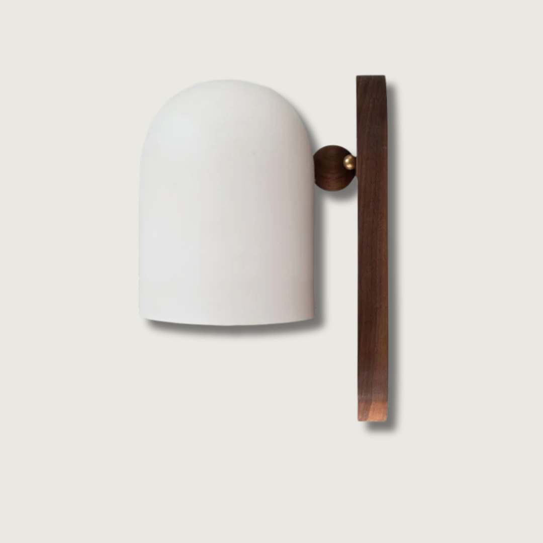 Walnut wood wall light with matte metal shade glowing on a living room wall