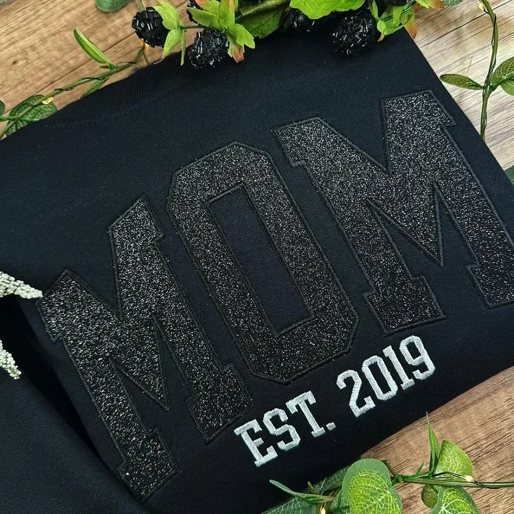 Embroidered mom sweatshirt featuring custom glitter-embroidered names of children on the sleeve.