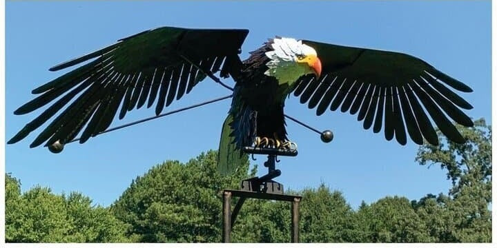 Metal eagle wind spinner with spinning wings in a garden bed