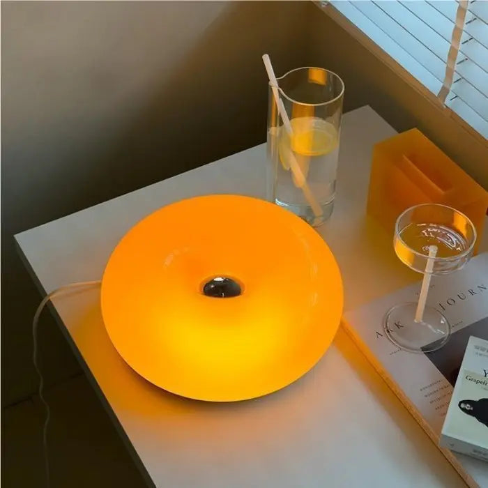 Ring shaped LED table lamp in glass and metal glowing warm white